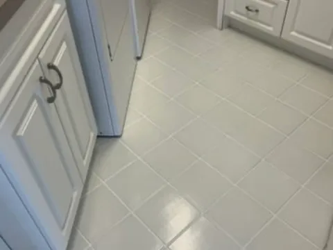 After: White ceramic kitchen floor with dark stained grout lines before and clean, even light grout after color sealing