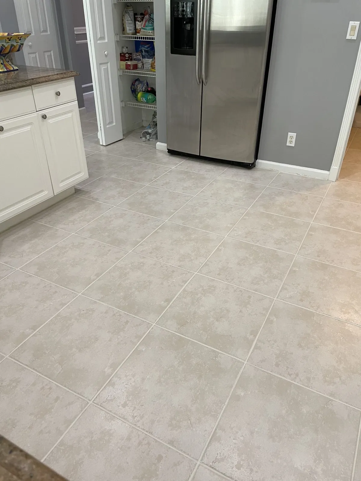 Clean light-colored kitchen tile floor with bright, even grout lines in a Palm Beach County home