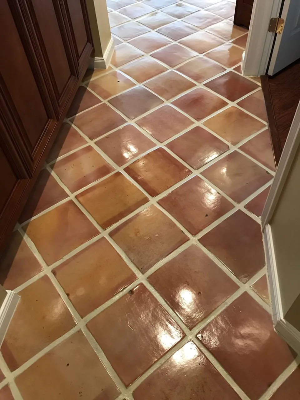 After: Mexican Saltillo tile hallway with dull tile and gray grout before, and glossy tile with bright grout after